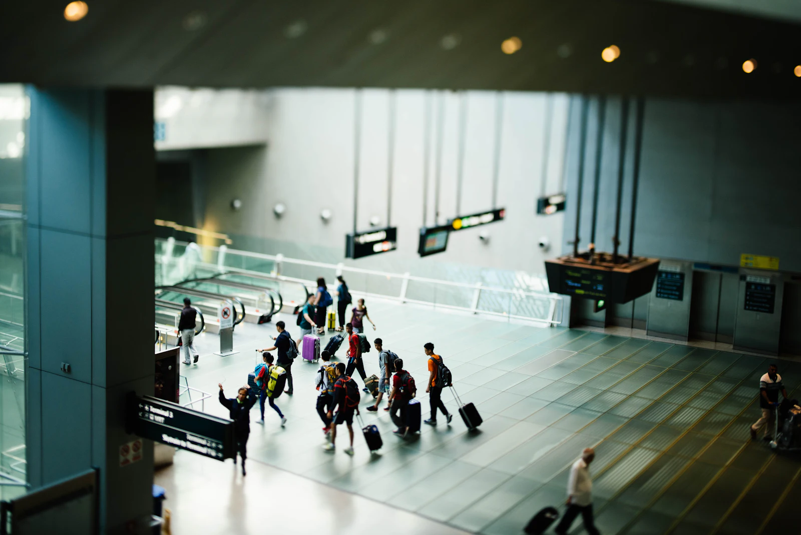 Passengers walking through a wide airport concourse between gates