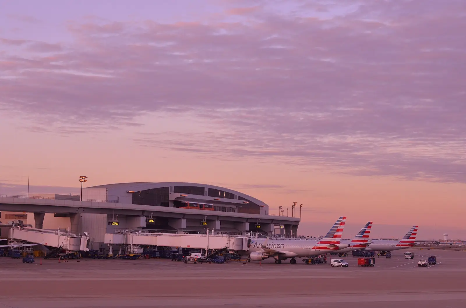 A terminal at Dallas-Fort Worth International Airport at dusk, with American Airlines tails at the gates