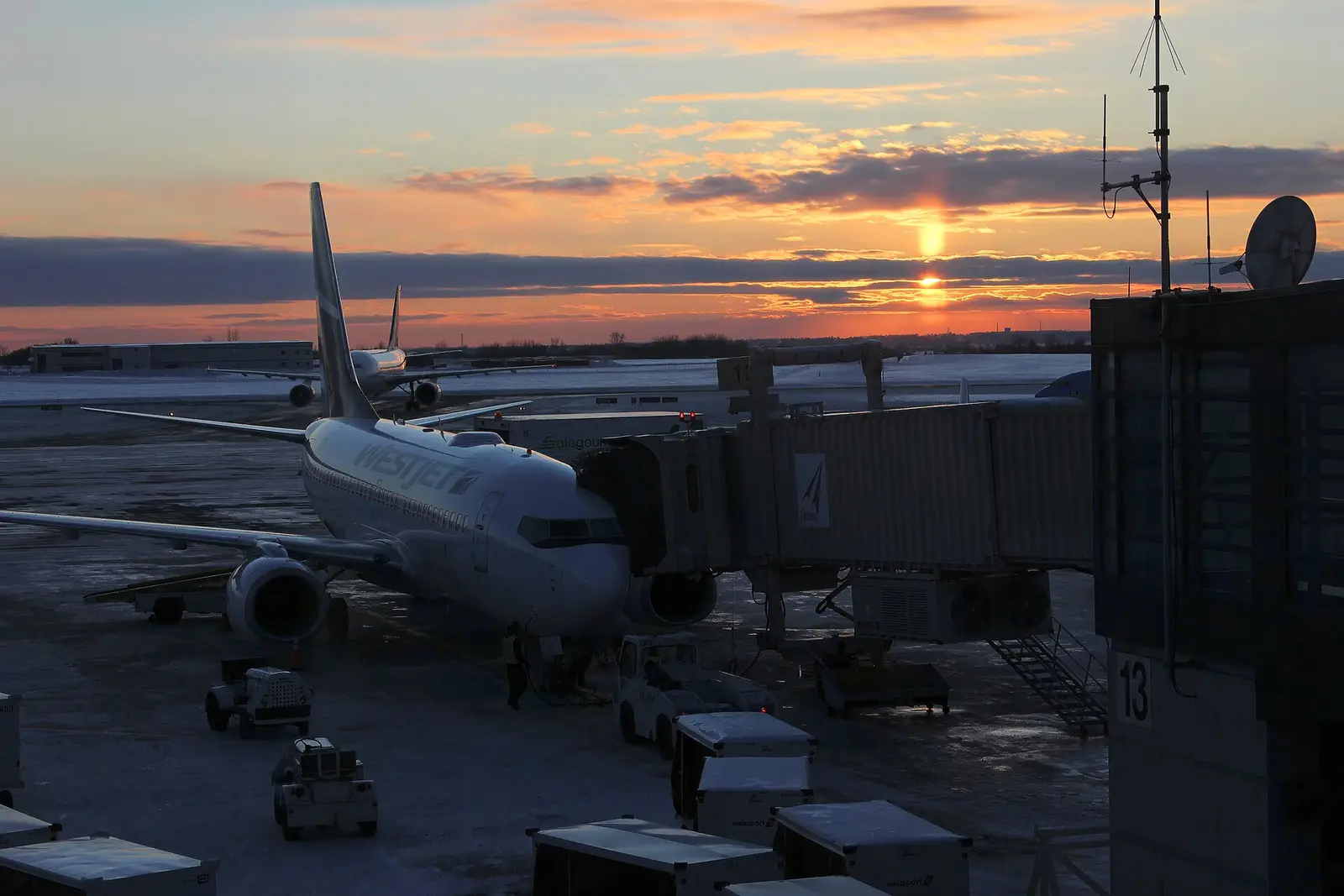 An airliner parked at a terminal gate at sunset